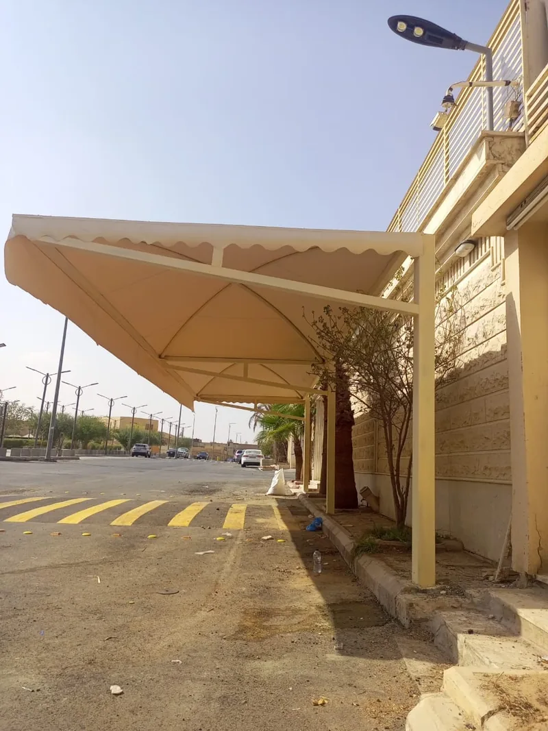 مظلة سيارات كابولي بقماش فاتح على طول رصيف شارع سكني