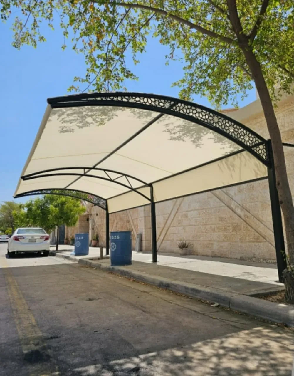 مظلة سيارات بقماش مشدود وحافة معدنية مزخرفة فوق ممر سيارات