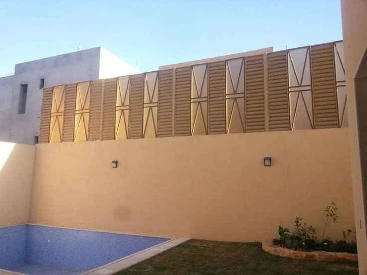 ألواح ساتر مزخرفة بلون بني أعلى سور فناء يضم مسبحًا