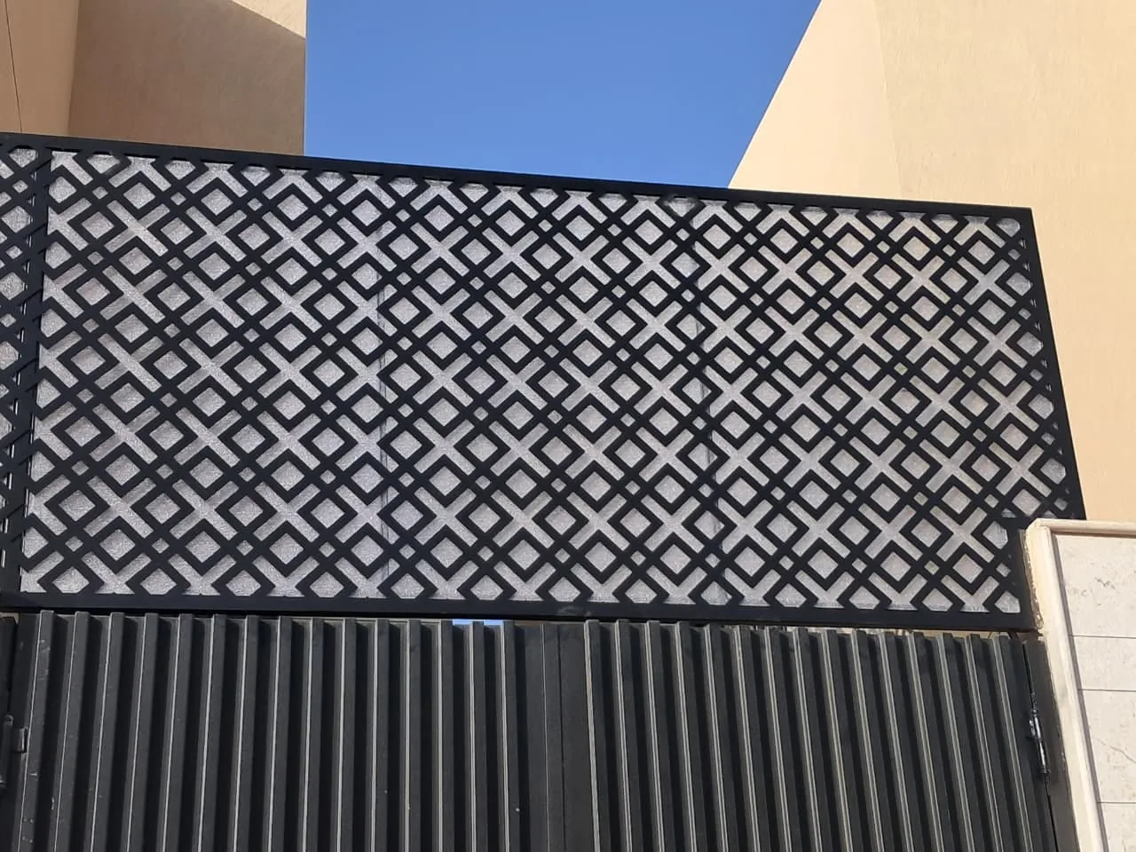 ساتر معدني أسود بألواح ليزر مفرغة بنقوش هندسية أعلى جدار