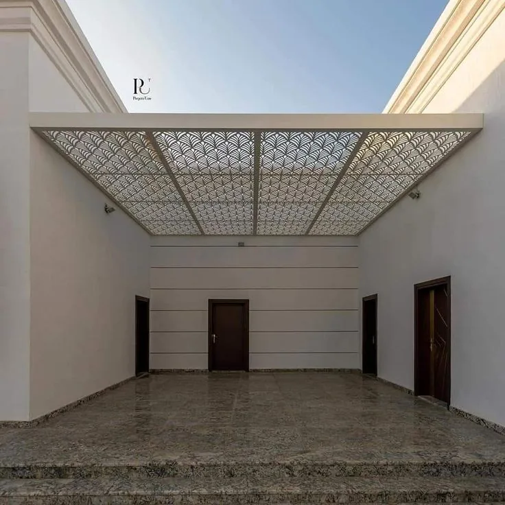 صالة داخلية واسعة بسقف مزخرف بنقوش هندسية وأرضية رخامية وبابين خشبيين