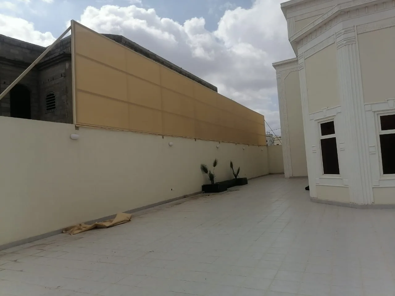 سطح منزل مسوَّر بألواح ساندوتش بانل بلون بيج مع أرضية بلاط فاتحة