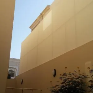 جدار مرتفع مكسو بألواح ساندوتش بانل بلون بيج بمحاذاة واجهة مبنى