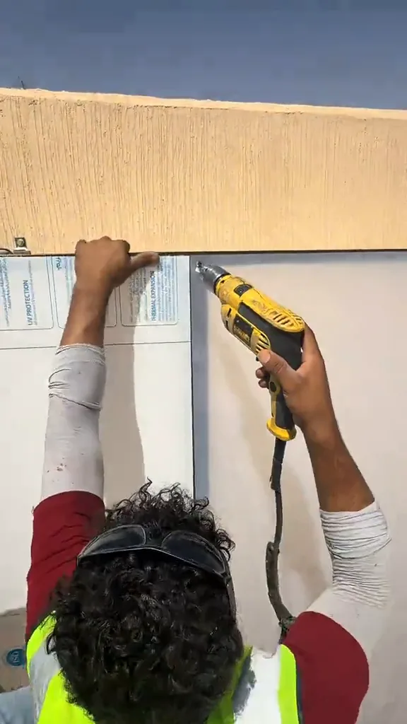 عامل يثبت لوح ساندوتش بانل جداري باستخدام مفك كهربائي